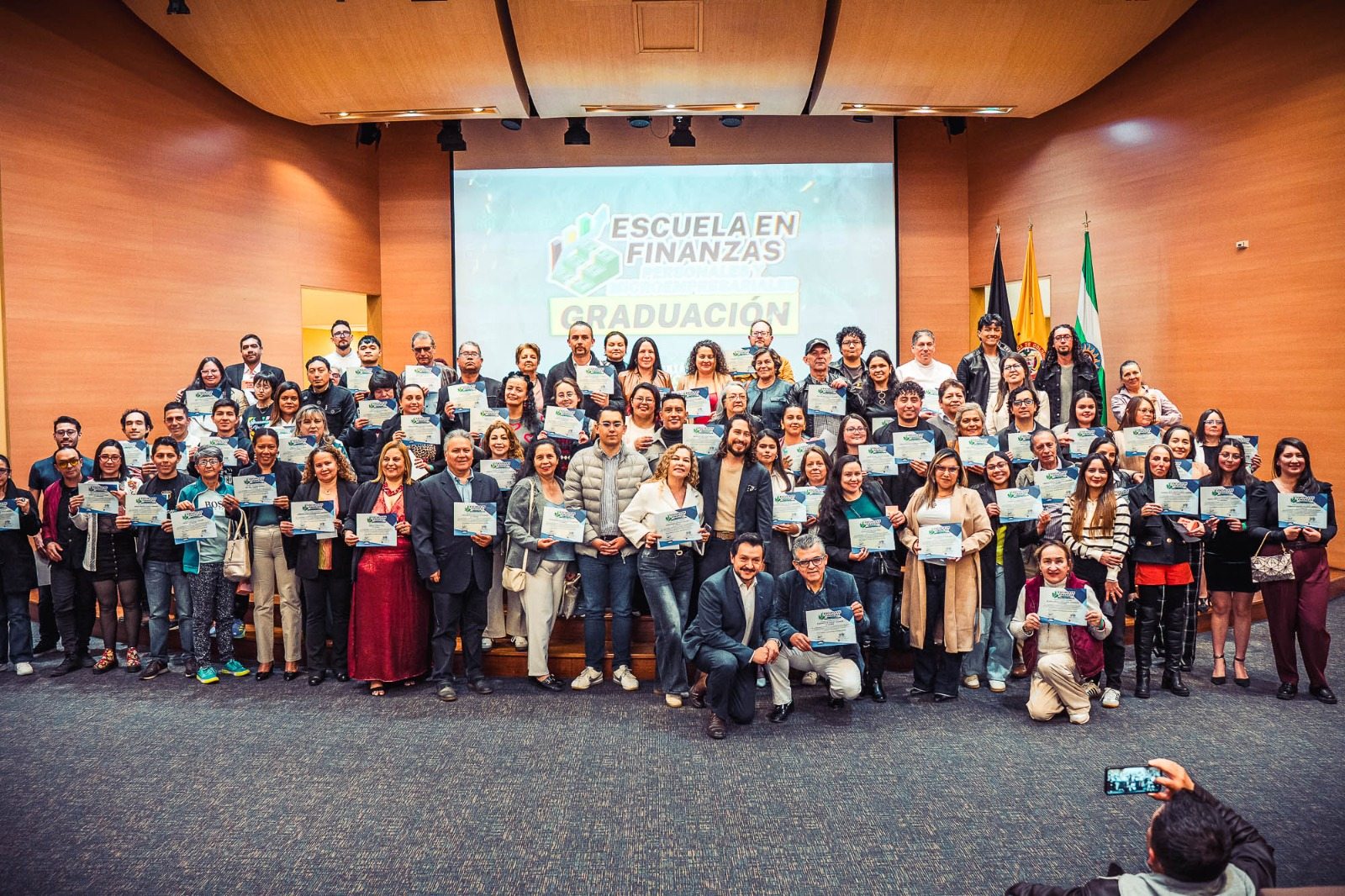 Graduandos de la Escuela en Finanzas posando con sus certificados en el auditorio