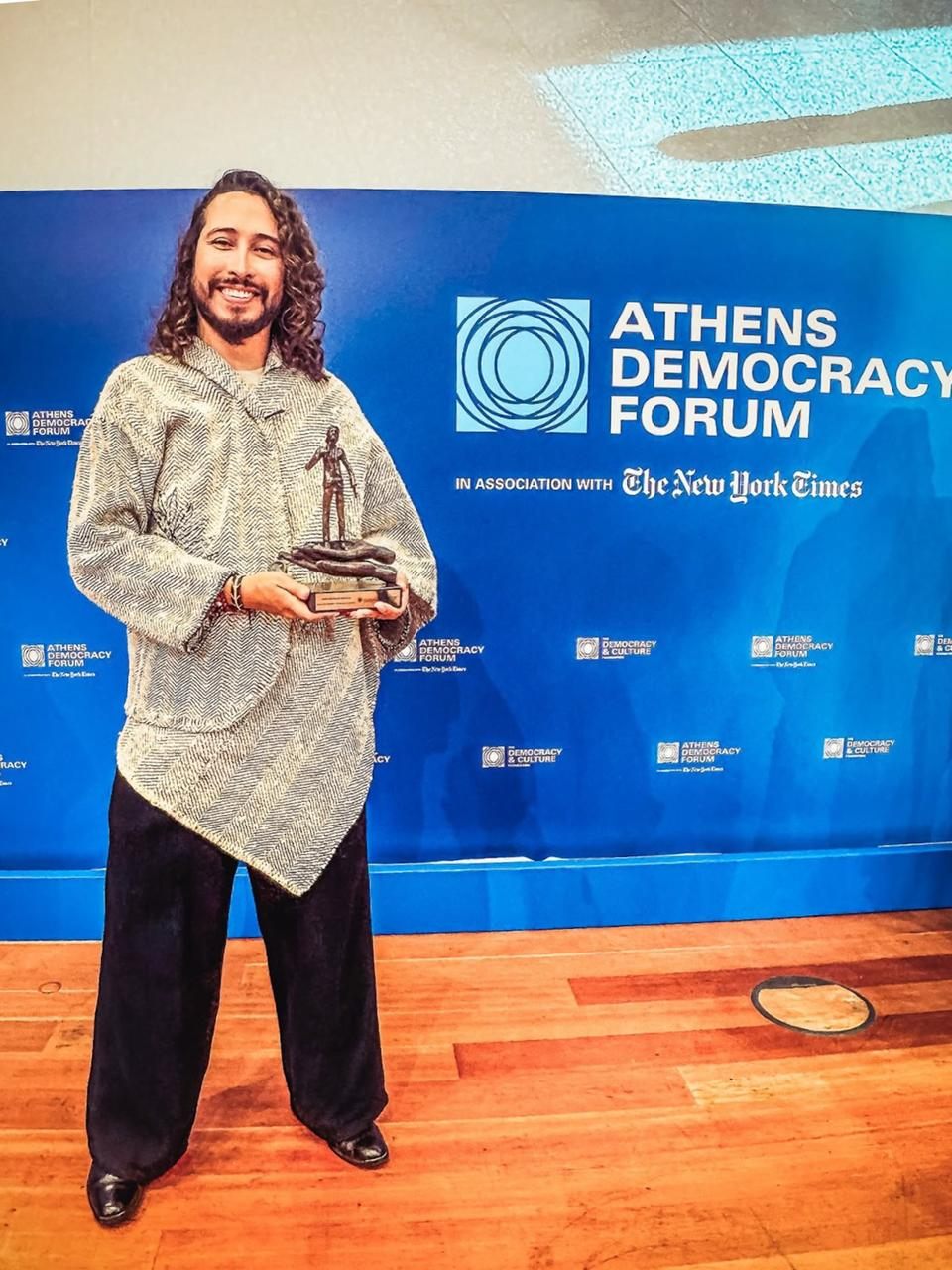Julián Sastoque sostiene el galardón del Premio Kofi Annan NextGen Democracy en el Athens Democracy Forum